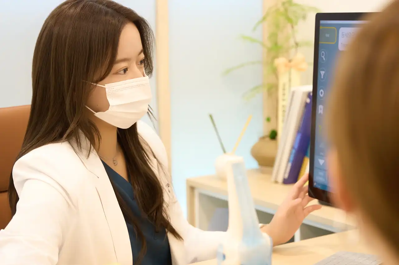 Dr. Jeonghyeon Kim talking with a patient while they look at a monitor together in the treatment room