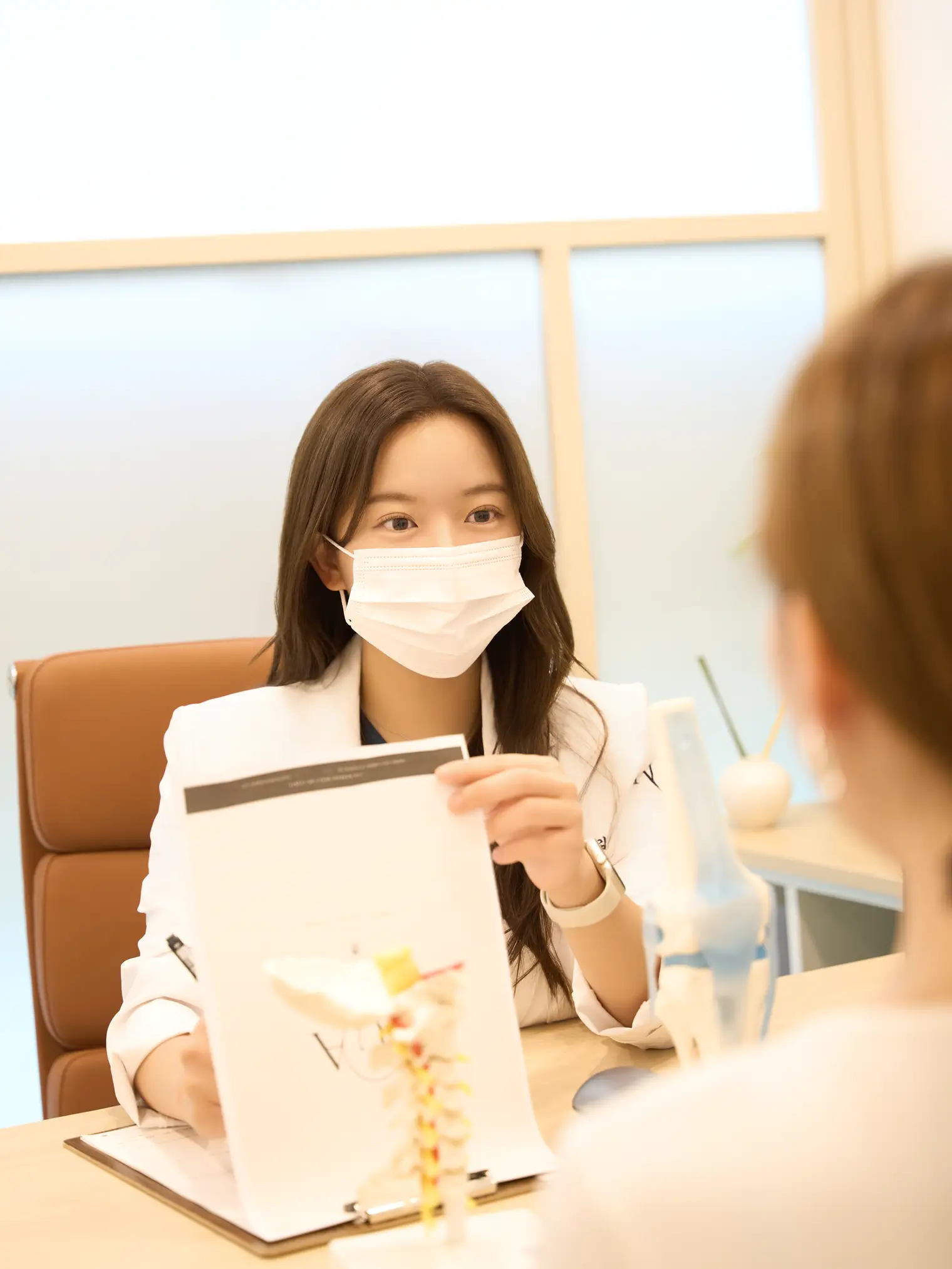 Dr. Jeonghyeon Kim holding up materials to explain to a patient