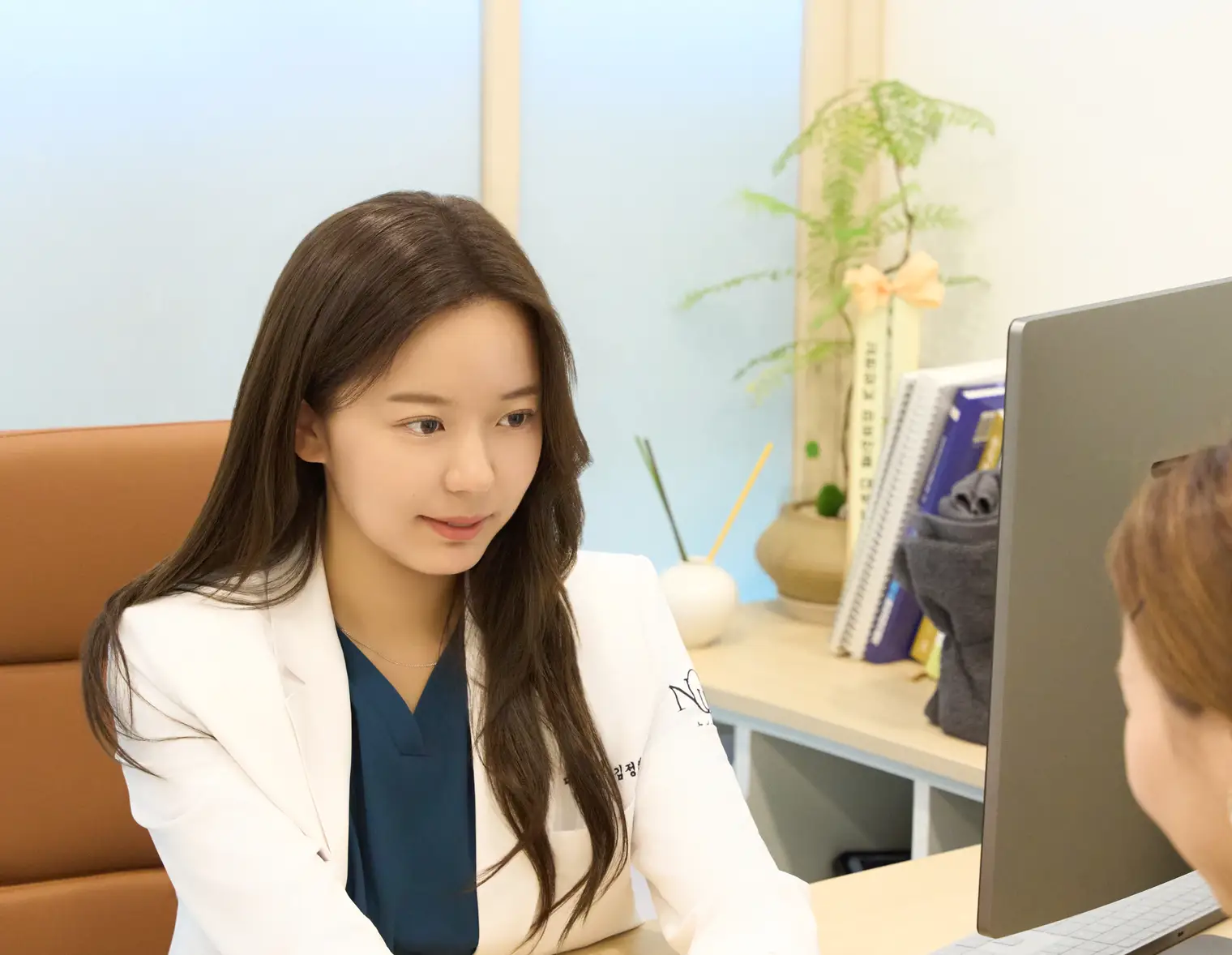 Dr. Jeonghyeon Kim at the desk, meeting a patient's eyes and listening