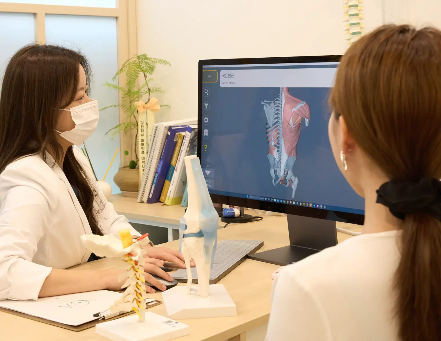 Explaining the painful area while looking at anatomy material on a monitor