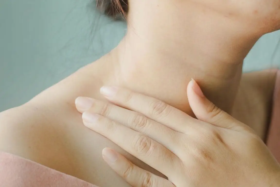 A woman holding her hand around her neck and collarbone