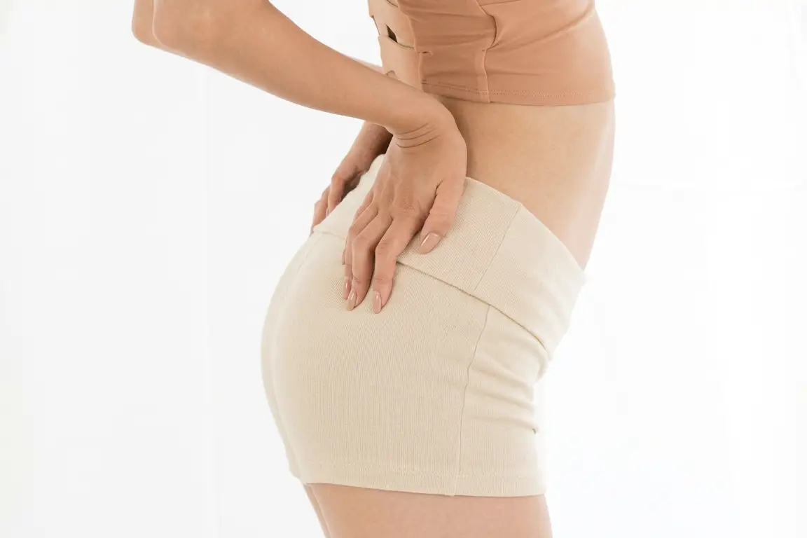 Side line of a woman's waist and thigh in grey shorts